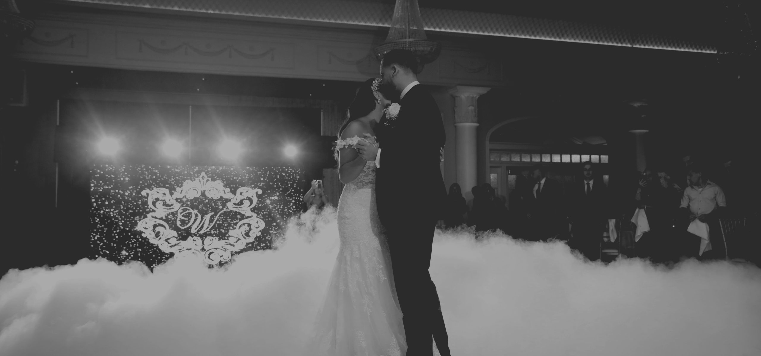 A couple's first dance on a cloud of dry ice under spotlights
