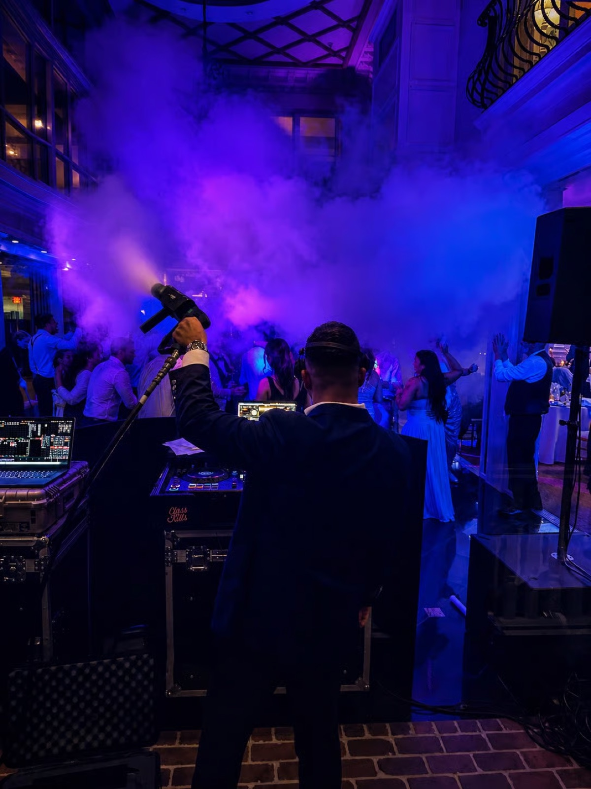 A DJ firing a CO2 cannon into a purple-lit dance floor