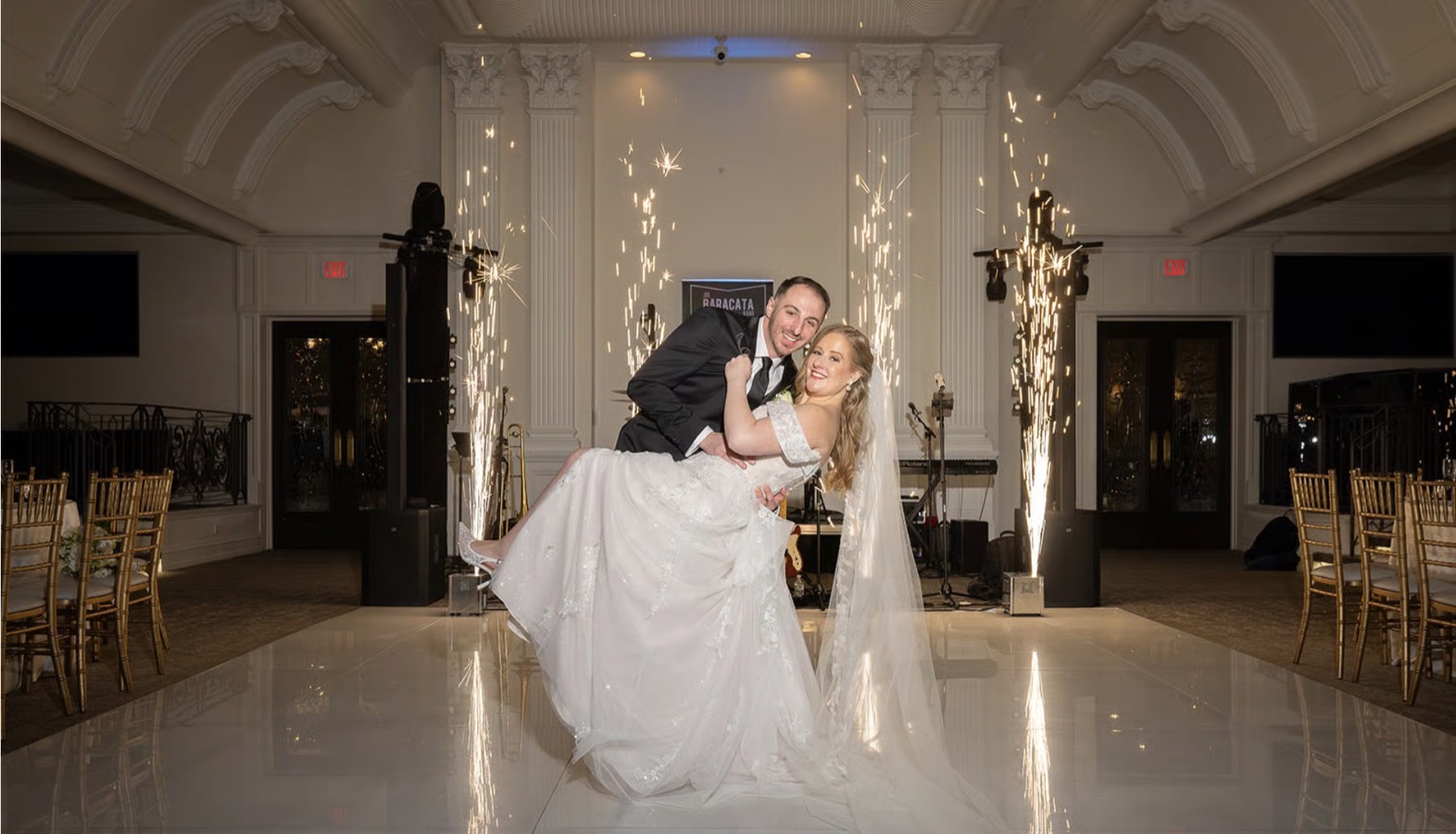 A bride and groom dipping between two cold-spark fountains on the dance floor