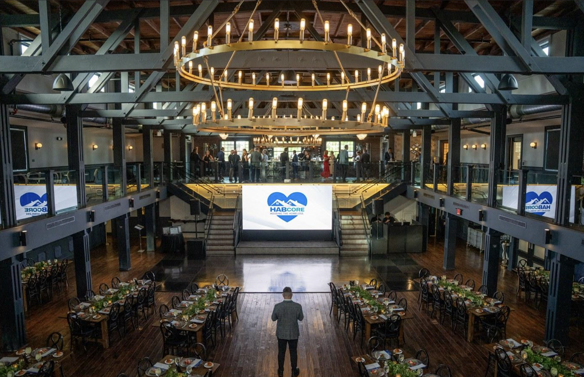 A branded corporate gala ballroom with stage screen and formal table settings