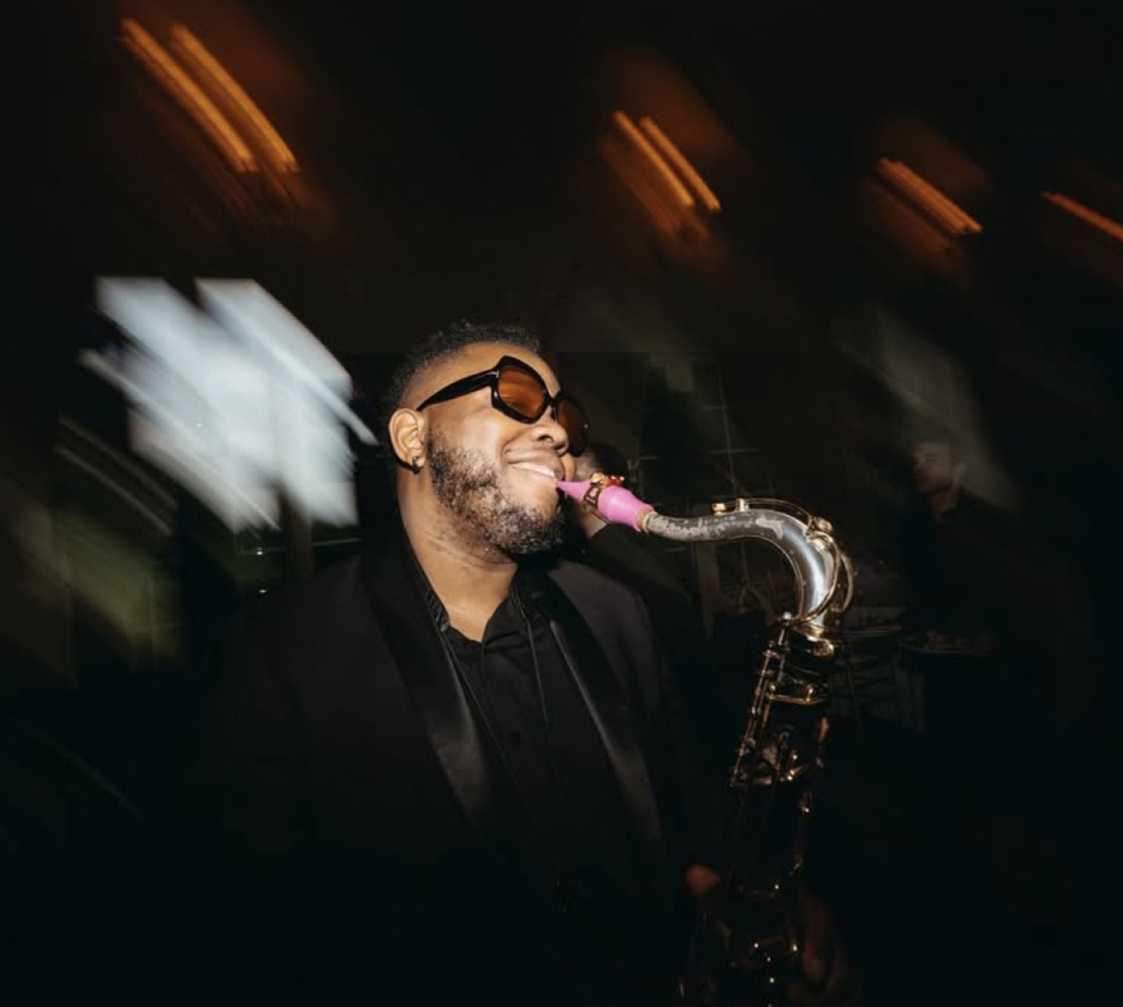 A saxophonist performing live over the DJ set at a reception