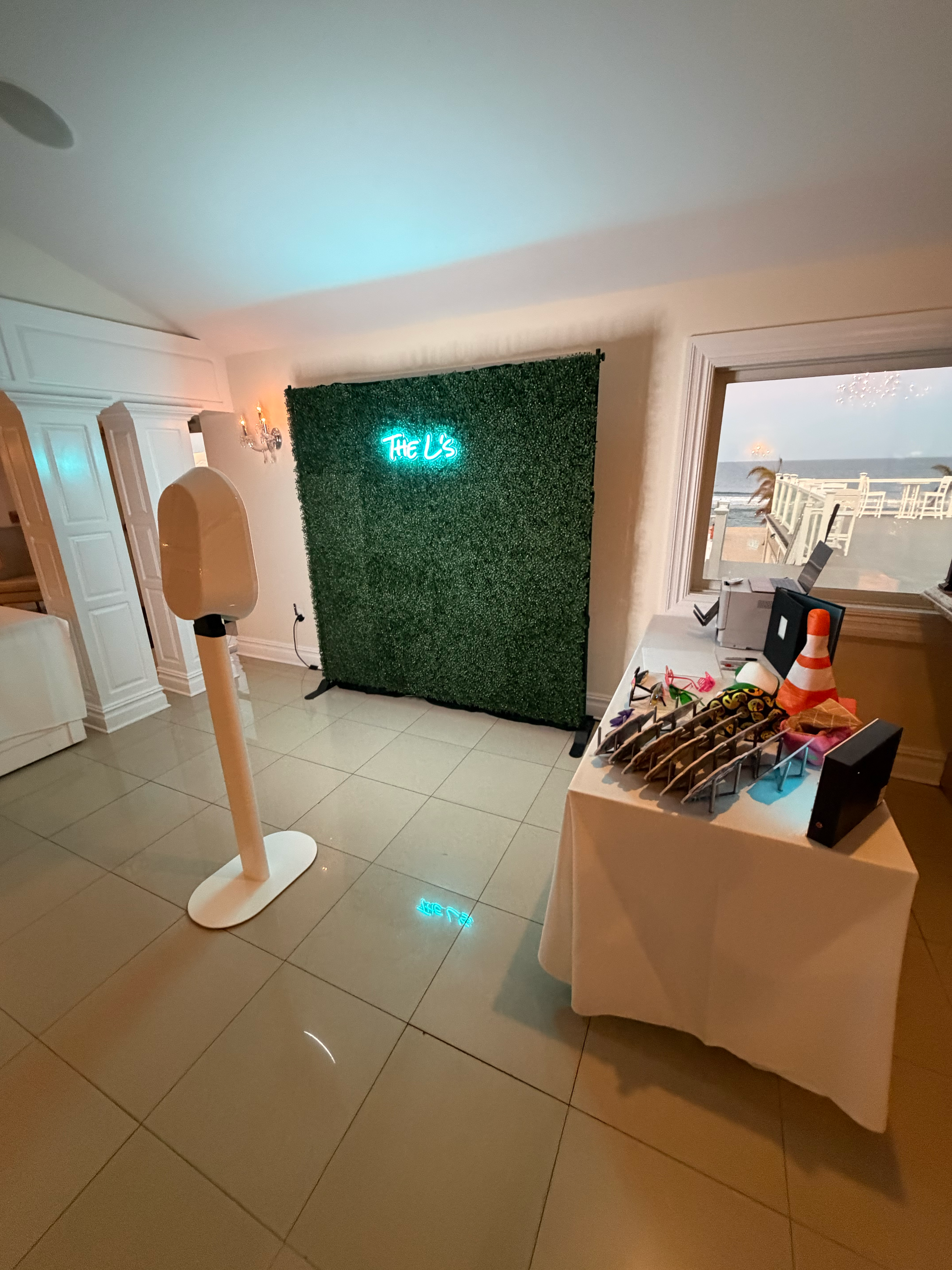 A photo booth setup with a custom neon-sign backdrop and a props table