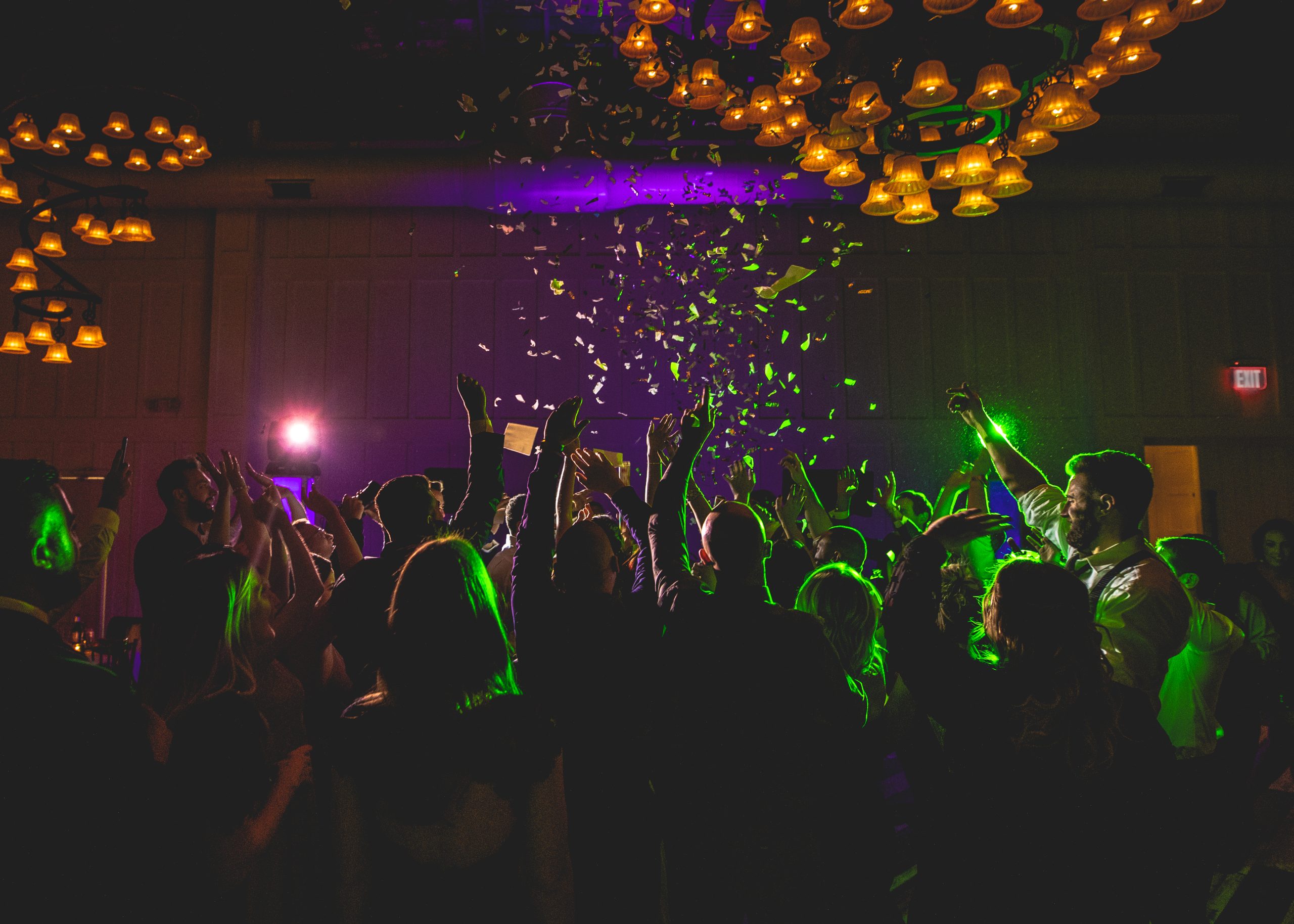 Confetti falling over a packed wedding dance floor under colored lights