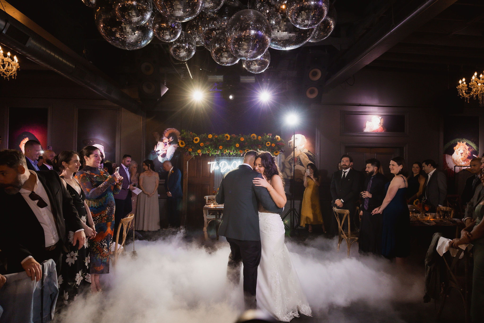 Confetti falling over a packed wedding dance floor under colored lights